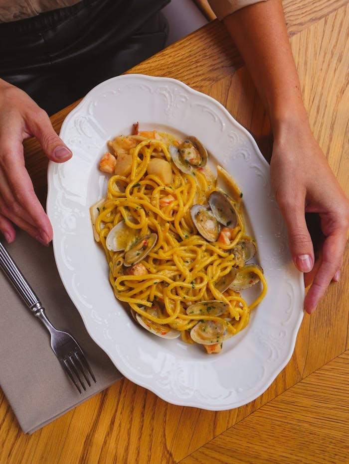 A flavorful seafood pasta dish served on a white ornate plate, ready to enjoy.